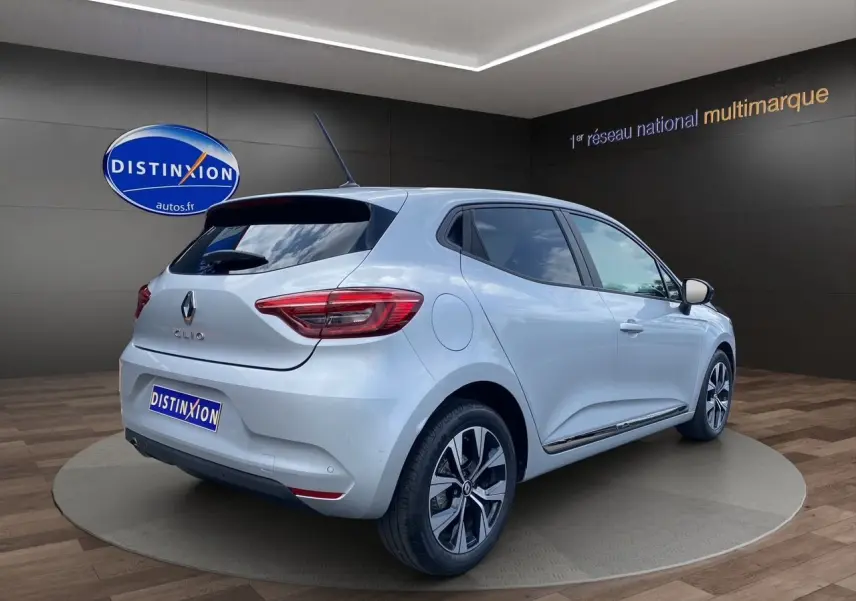 Renault Clio V gris Highland vue 3/4 arrière droit, jantes alliage et vitres teintées en showroom.