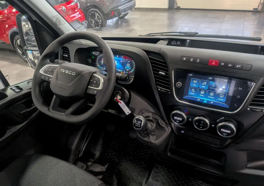 Vue intérieure côté conducteur du tableau de bord de l'Iveco Daily Fourgon blanc 2025 avec volant multifonction et écran tactile.