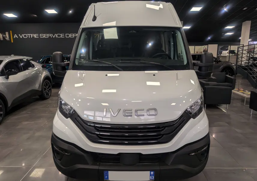 Vue de face du fourgon Iveco Daily blanc 2025 en showroom, mettant en valeur la calandre noire et le logo Iveco.