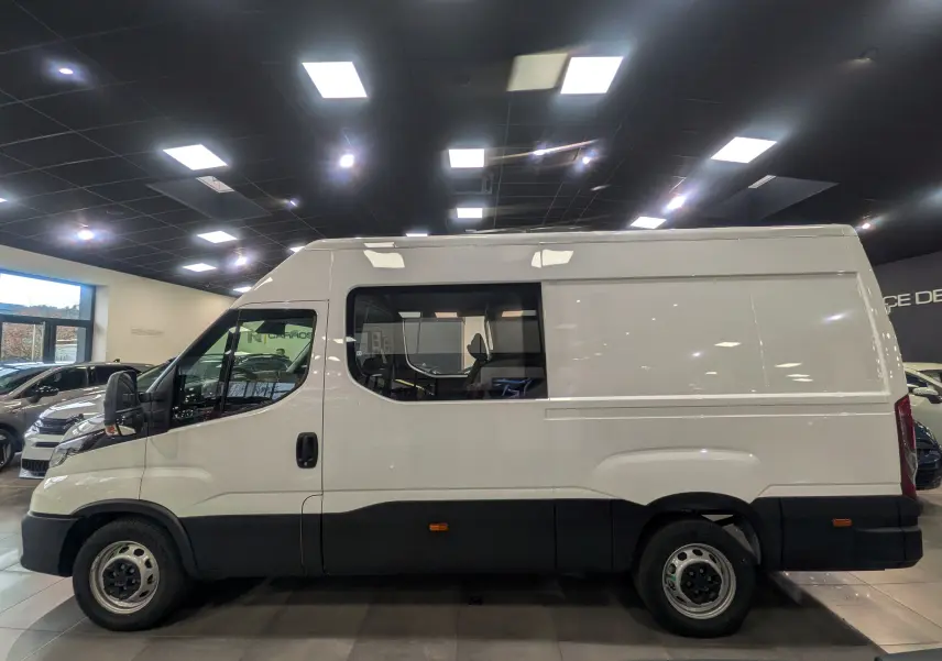 Vue de profil côté gauche d'un fourgon Iveco Daily blanc 2025 avec fenêtre latérale et carrosserie haute.