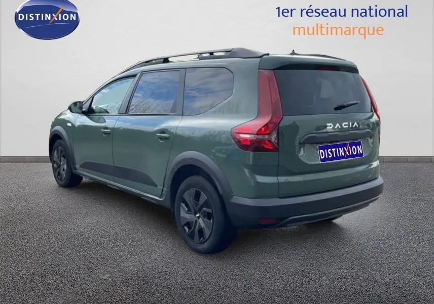 Vue 3/4 arrière gauche d'un Dacia Jogger 2025 kaki lichen avec barres de toit et jantes noires.