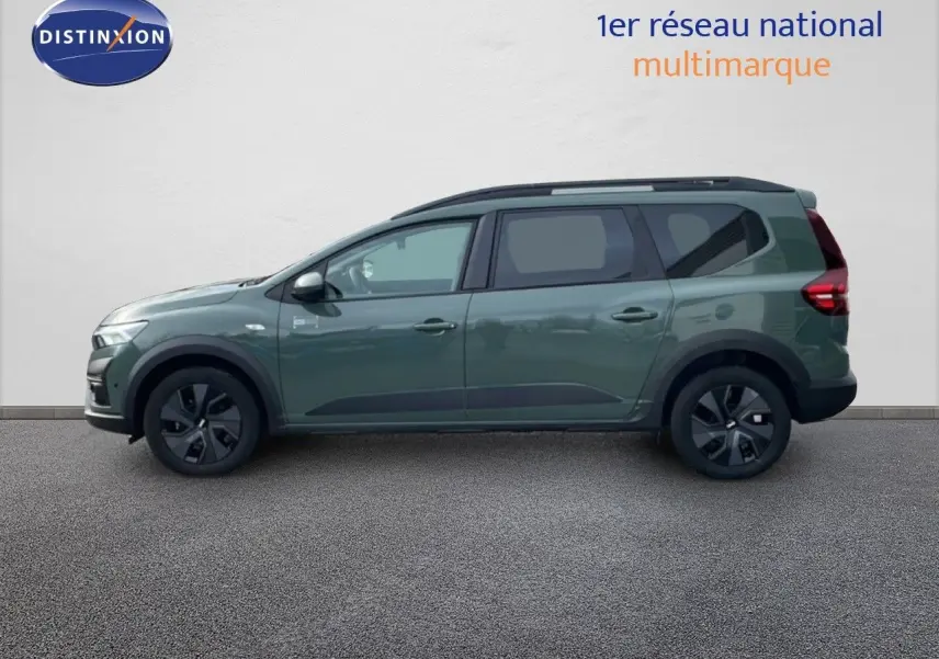 Profil droit d'un Dacia Jogger 2025 kaki lichen avec jantes noires et barres de toit visibles.