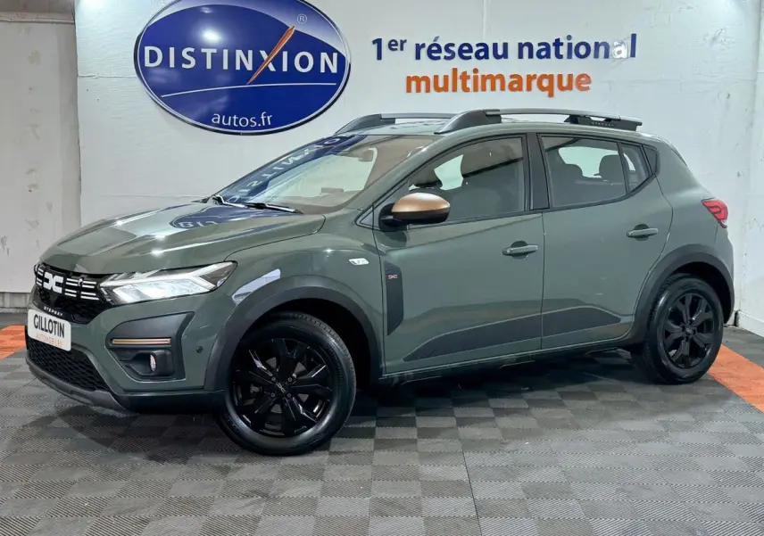 Vue 3/4 avant droite d'une Dacia Sandero Extreme+ TCe 110 2024 verte avec jantes noires et barres de toit assorties.