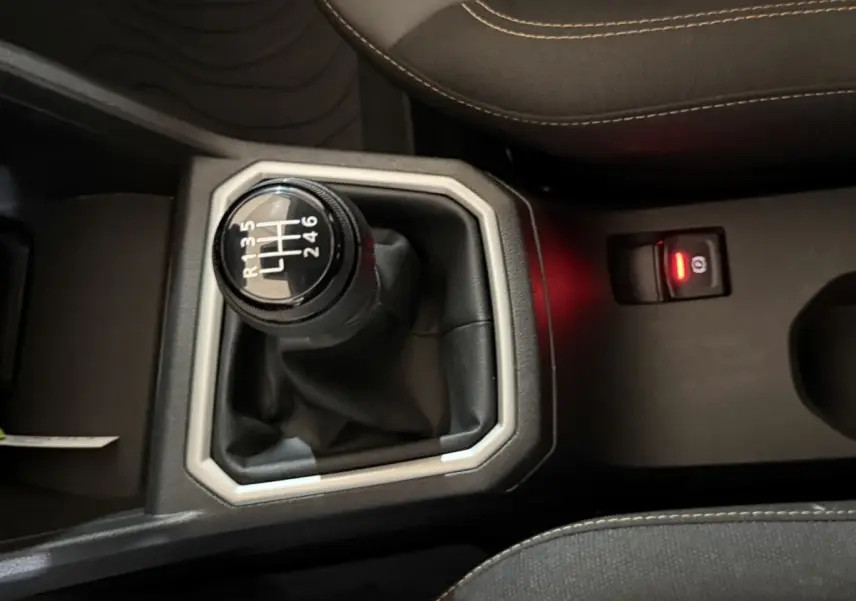 Gros plan sur le levier de vitesses manuel noir et gris de la Dacia Sandero Extreme+ TCe 110, avec coutures beige visibles.