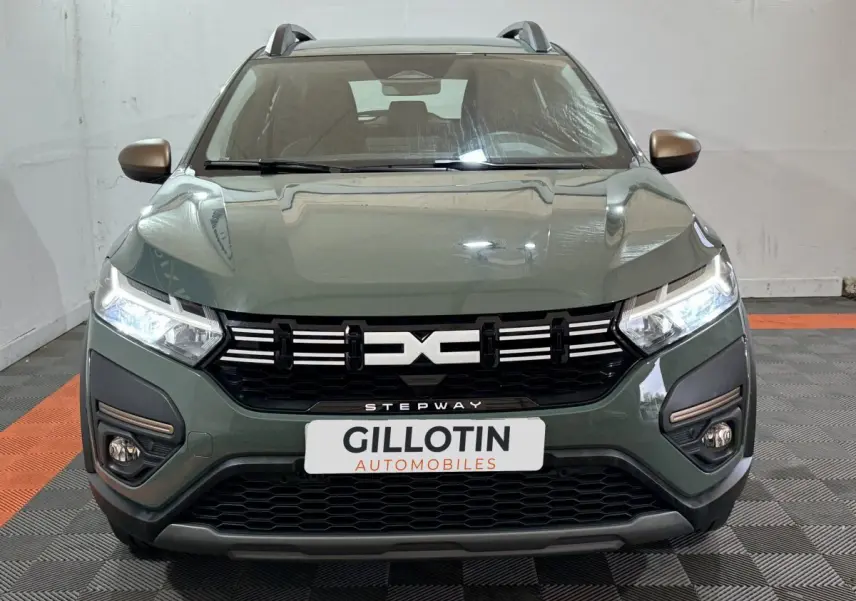 Vue avant d'une Dacia Sandero Extreme+ TCe 110 2024 vert avec phares LED allumés et calandre noire distinctive.