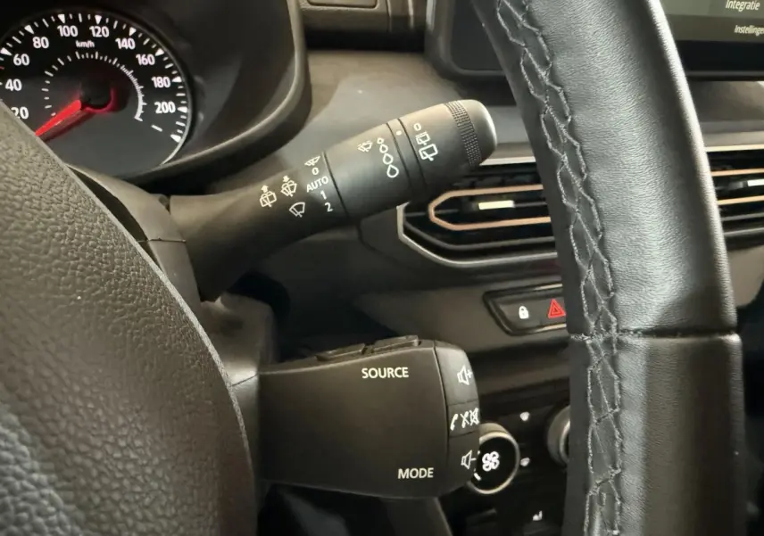 Gros plan sur la commande multifonction et le volant cuir noir du tableau de bord de la Dacia Sandero 2024.