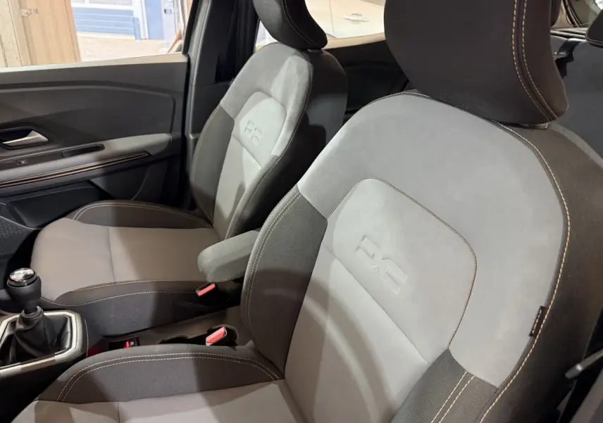 Vue intérieure rapprochée des sièges avant gris et noirs avec logo Extreme+ sur une Dacia Sandero 2024.