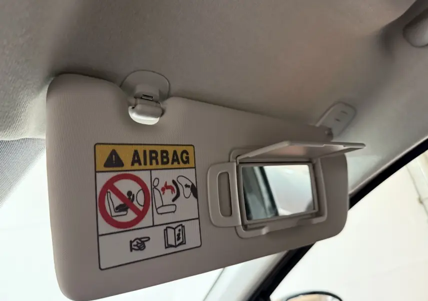 Vue rapprochée du pare-soleil côté conducteur avec miroir et avertissement airbag dans une Dacia Sandero 2024.