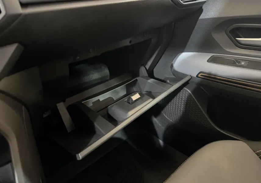 Vue intérieure côté passager du coffre à gants ouvert de la Dacia Sandero Extreme+ TCe 110 2024, avec tableau de bord noir.