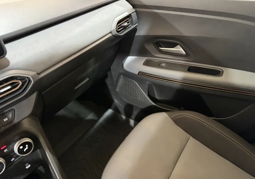 Vue intérieure côté passager avant de la Dacia Sandero Extreme+ 2024, avec sellerie grise et tableau de bord noir.
