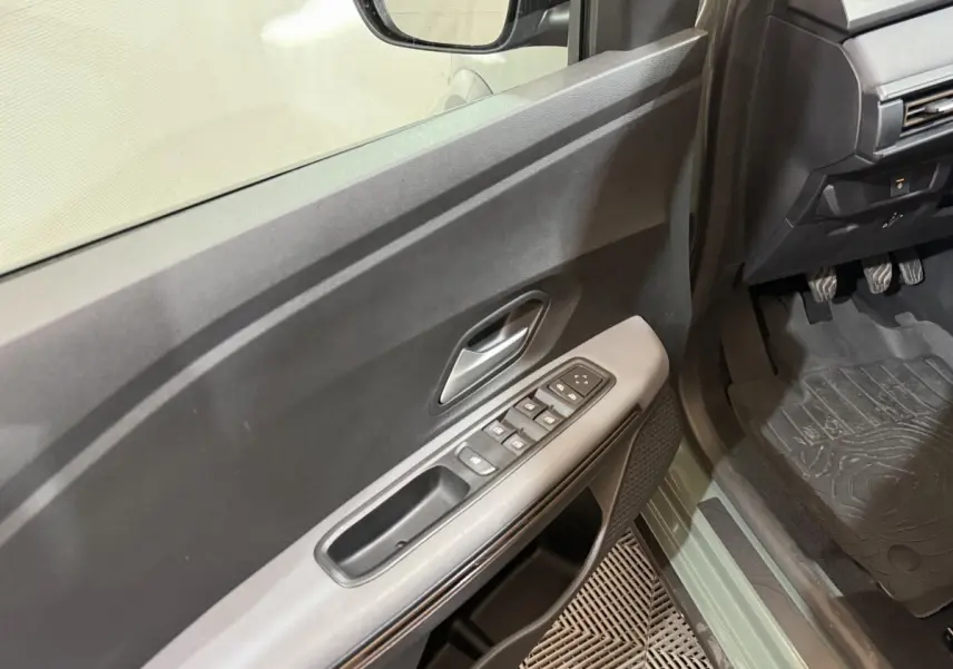 Vue intérieure côté conducteur de la porte et seuil vert d'une Dacia Sandero Extreme+ TCe 110 2024 avec commandes de vitres.