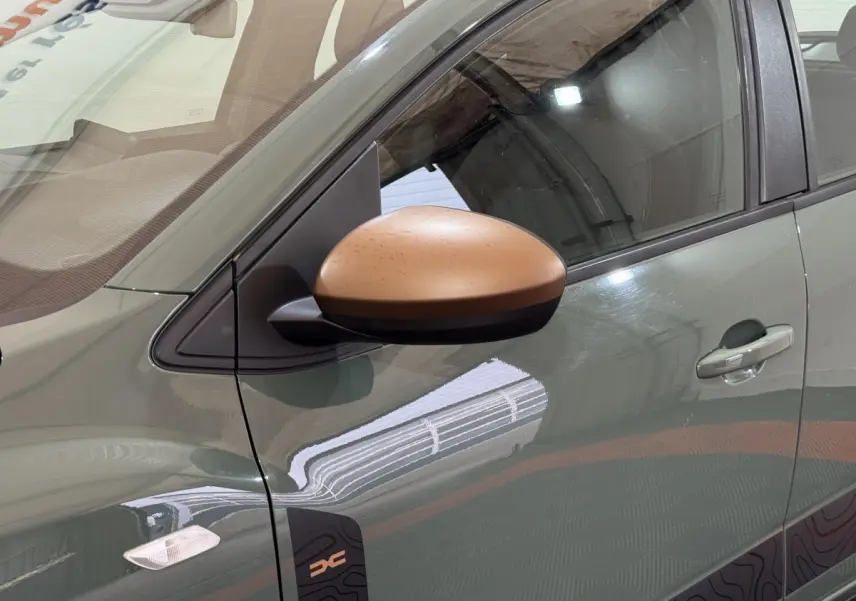Gros plan sur le rétroviseur cuivre et la portière côté gauche d'une Dacia Sandero Extreme+ vert 2024.