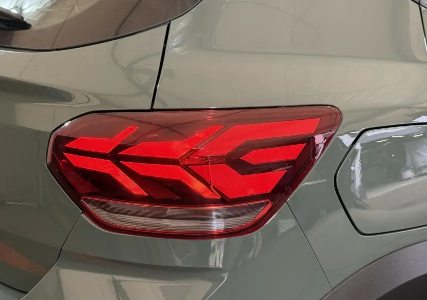 Gros plan sur le feu arrière droit rouge d’une Dacia Sandero Extreme+ TCe 110 vert 2024, avec la trappe à carburant visible.