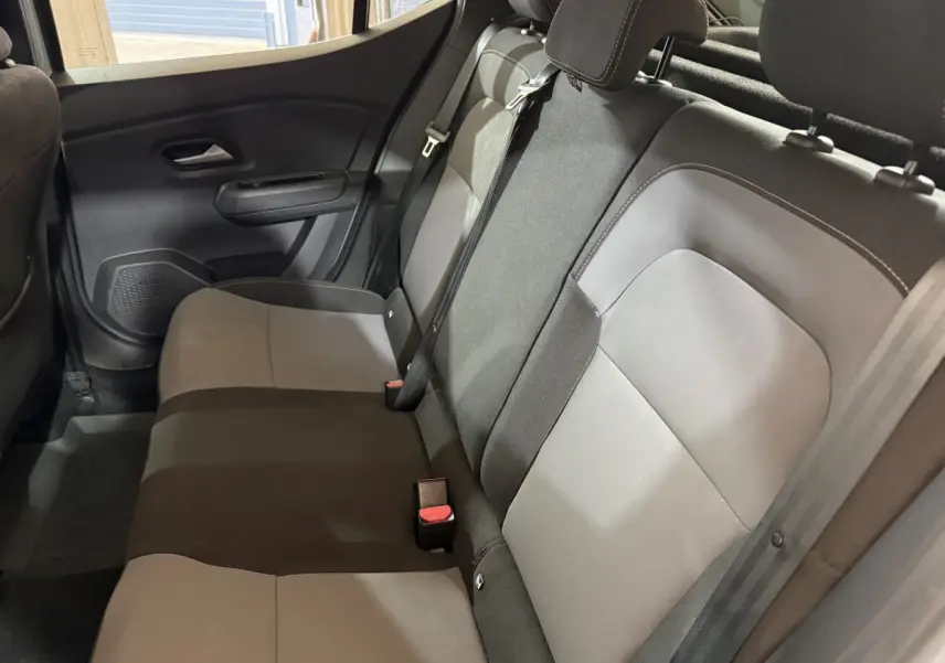 Vue côté droit de la banquette arrière bicolore gris et noir de la Dacia Sandero 2024, avec appuie-têtes et ceintures visibles.