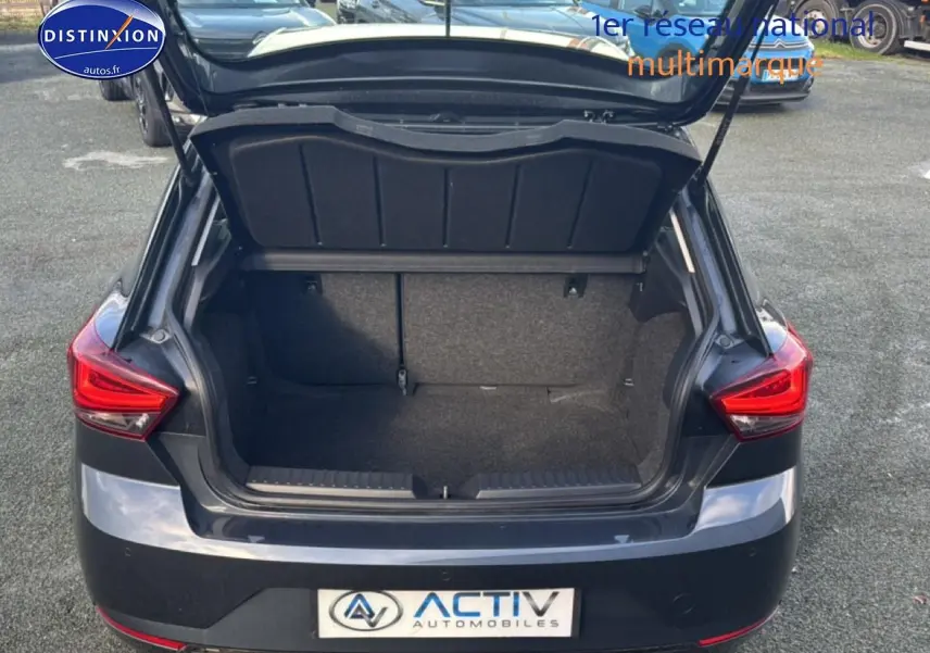 Vue arrière d'une SEAT Ibiza 1.0 TSI 95 Copa gris magnétique avec coffre ouvert montrant l'espace de chargement.