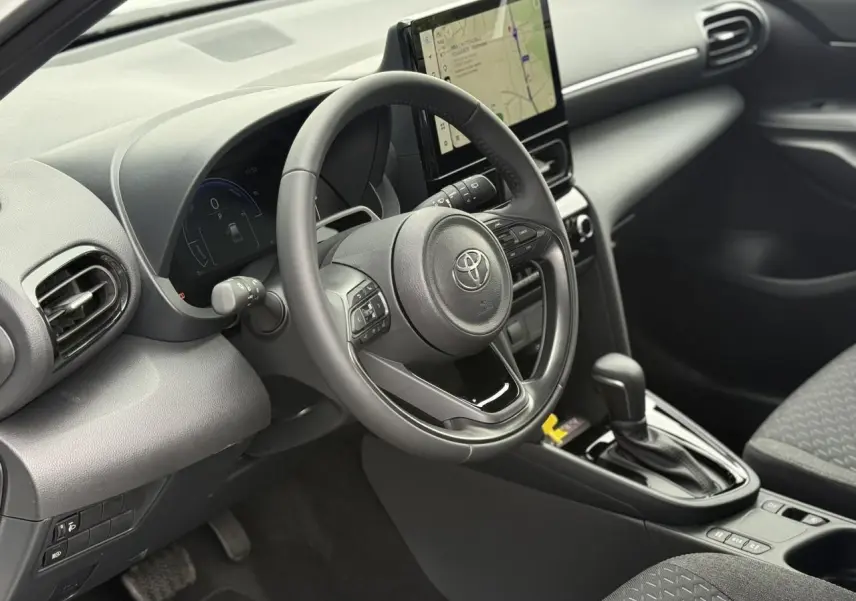 Vue intérieure côté conducteur de la Toyota Yaris Cross 2026, tableau de bord noir avec écran tactile et volant multifonction.