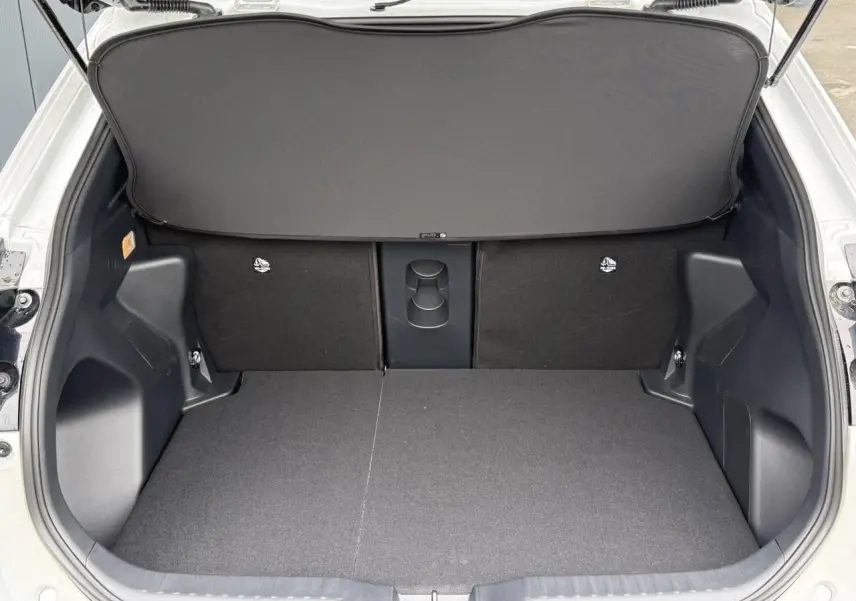 Coffre ouvert vu de l'arrière d'une Toyota Yaris Cross blanc lunaire avec plancher plat et sièges arrière rabattables.