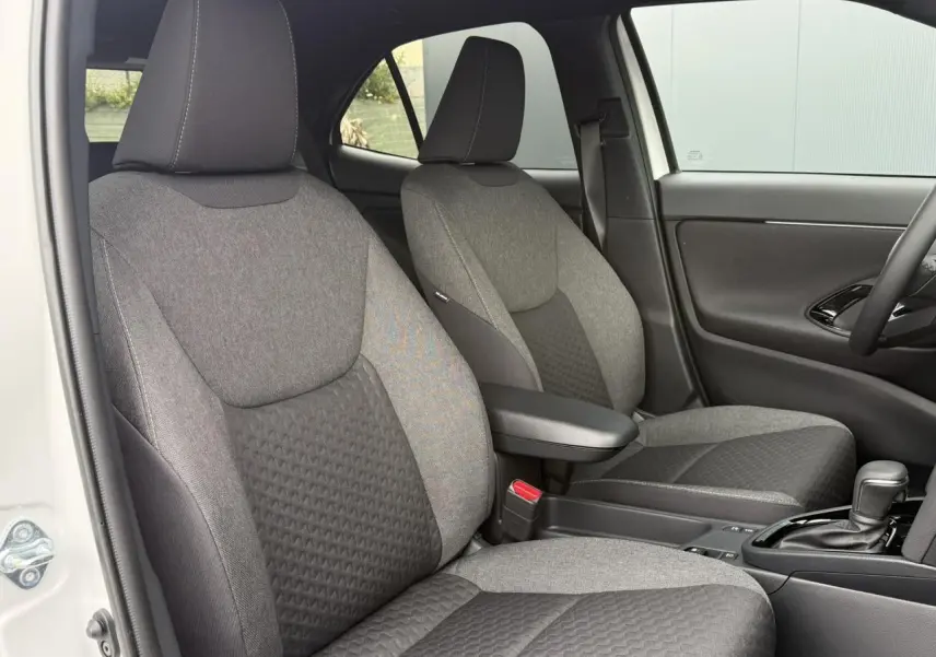 Vue intérieure côté gauche des sièges avant gris foncé et clair de la Toyota Yaris Cross 1.5 Hybrid 116 Design blanche.