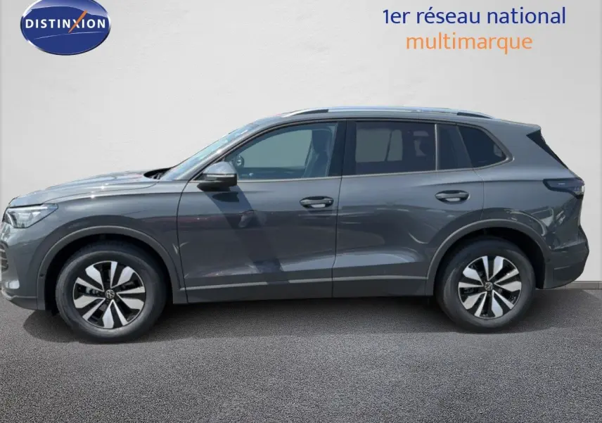 Vue de profil côté gauche d'un Volkswagen Tiguan gris dauphin métal, SUV compact avec jantes alliage bicolores.