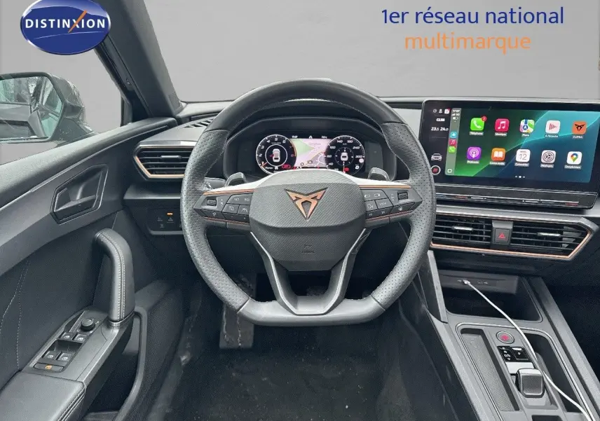 Vue intérieure du poste de conduite de la CUPRA LEON ST 2024 avec volant multifonction et écran tactile central lumineux.