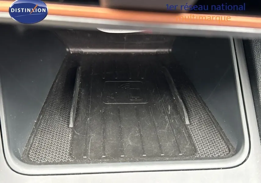 Surface de recharge sans fil noire dans l'habitacle d'une CUPRA LEON ST 2024, vue en gros plan.