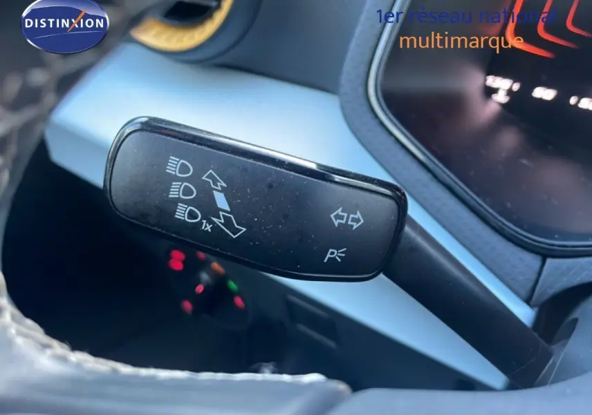 Gros plan sur la manette de clignotant à gauche du volant dans l’habitacle du SEAT Arona blanc toit gris.