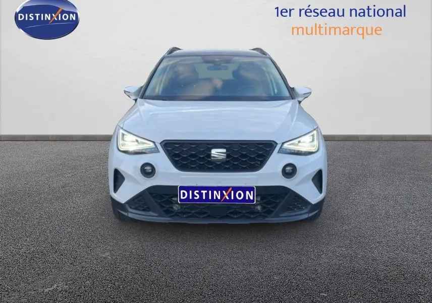Vue frontale du SEAT Arona blanc avec toit gris, phares LED allumés et calandre noire distinctive.