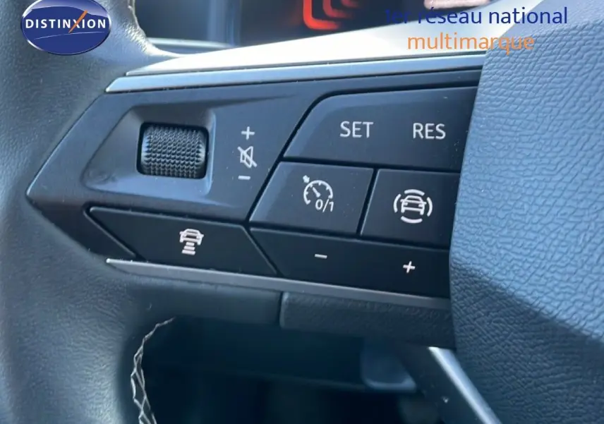 Gros plan sur les commandes de régulateur de vitesse au volant d’un SEAT Arona blanc toit gris, intérieur noir.