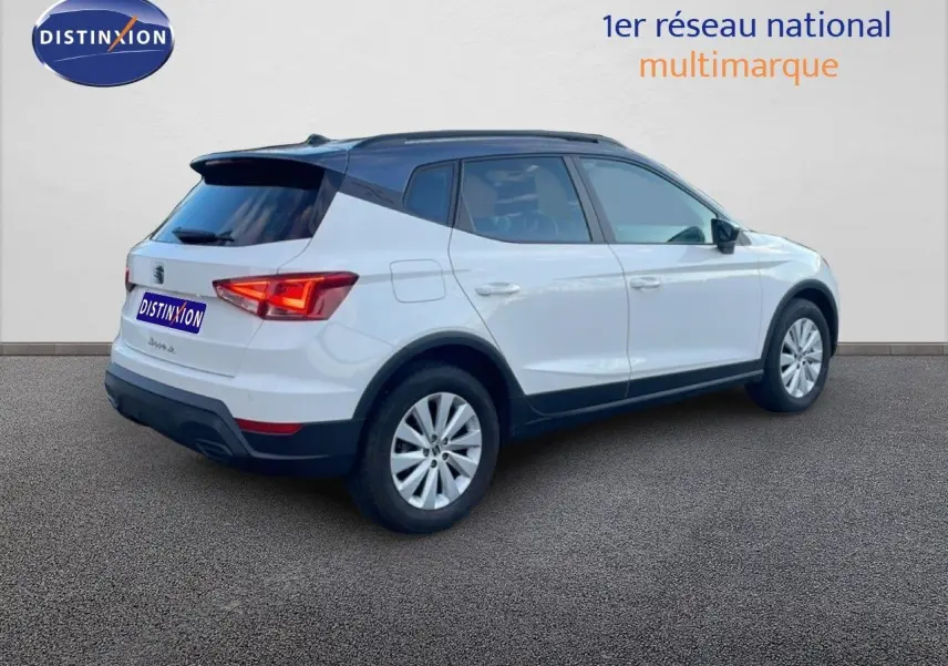 Vue 3/4 arrière droite d'un SEAT Arona blanc avec toit gris, mettant en valeur son design compact et moderne.