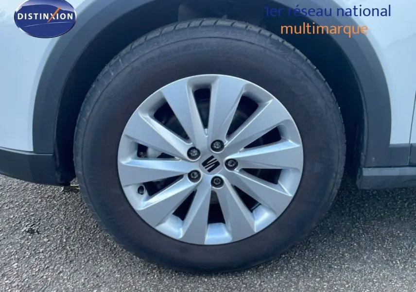 Gros plan sur la roue avant gauche blanche du SEAT Arona 2025 avec jante argentée et logo central visible.