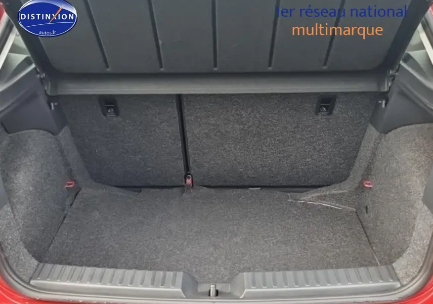 Coffre ouvert vu de l'arrière d'une SEAT Ibiza rouge désir avec banquette arrière rabattable visible.