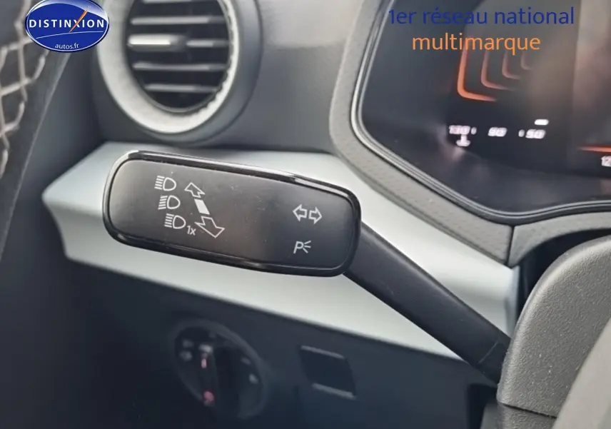 Gros plan sur la manette de clignotant à gauche du volant d'une SEAT Ibiza 2025 rouge désir, intérieur gris.