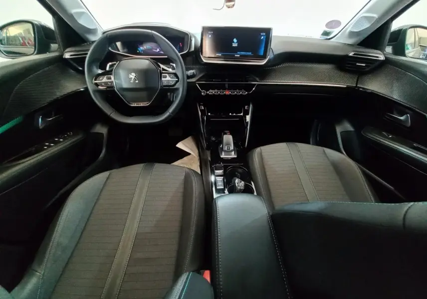 Vue intérieure avant de la Peugeot 208 noire, montrant le volant compact, l'écran tactile central et les sièges tissu gris.