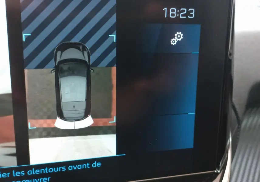 Affichage tactile intérieur montrant la vue aérienne en noir de la Peugeot 208 PureTech lors d'une manœuvre.