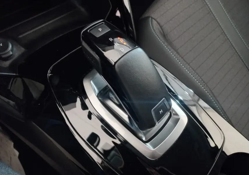 Le levier de vitesse automatique noir de la Peugeot 208 PureTech 100 vu en gros plan intérieur côté conducteur.