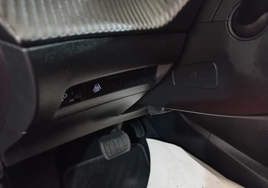 Détail intérieur côté gauche montrant les commandes sous le tableau de bord et la pédale de frein d'une Peugeot 208 noire.