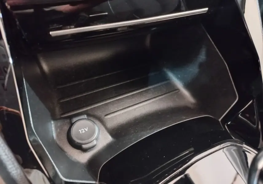 Prise 12V en gros plan dans la console centrale noire de la Peugeot 208 PureTech 100 S&S EAT8 Allure Pack 2022.