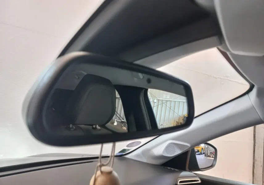 Vue intérieure du rétroviseur central d'une Peugeot 208 noire, avec appui-tête et partie du tableau de bord visibles.