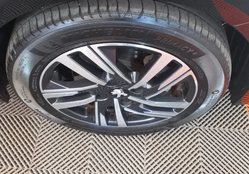 Gros plan sur la jante alliage noire et argentée avec logo Peugeot, montée sur pneu Michelin Primacy 4.