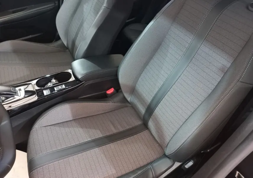Gros plan sur les sièges avant gris et noirs de la Peugeot 208 PureTech 100 Allure Pack, avec console centrale visible.