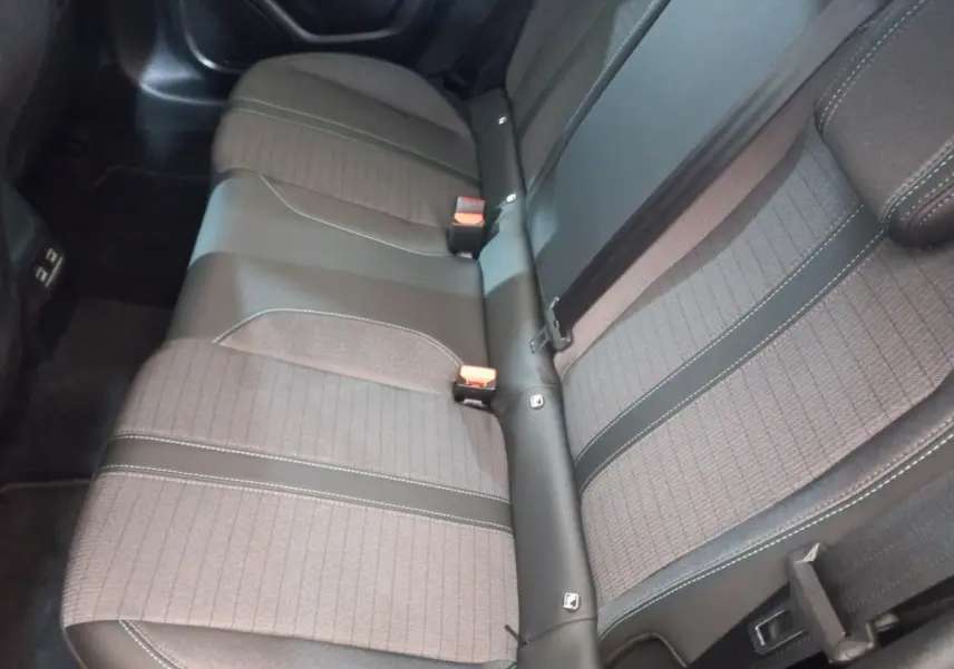 Vue rapprochée de la banquette arrière grise de la Peugeot 208 PureTech 100, montrant les ceintures et les textures du tissu.
