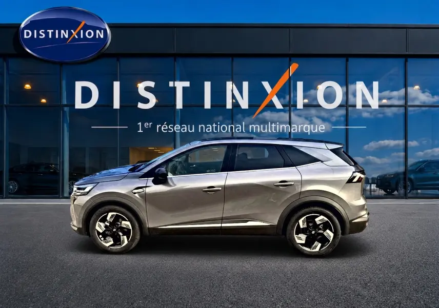 Renault Symbioz gris cassiopée en profil droit devant une vitrine avec logo Distinxion.