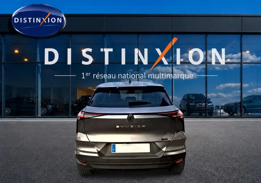 Vue arrière d'un Renault SYMBIOZ gris cassiopée garé devant une vitrine avec logo Distinxion.