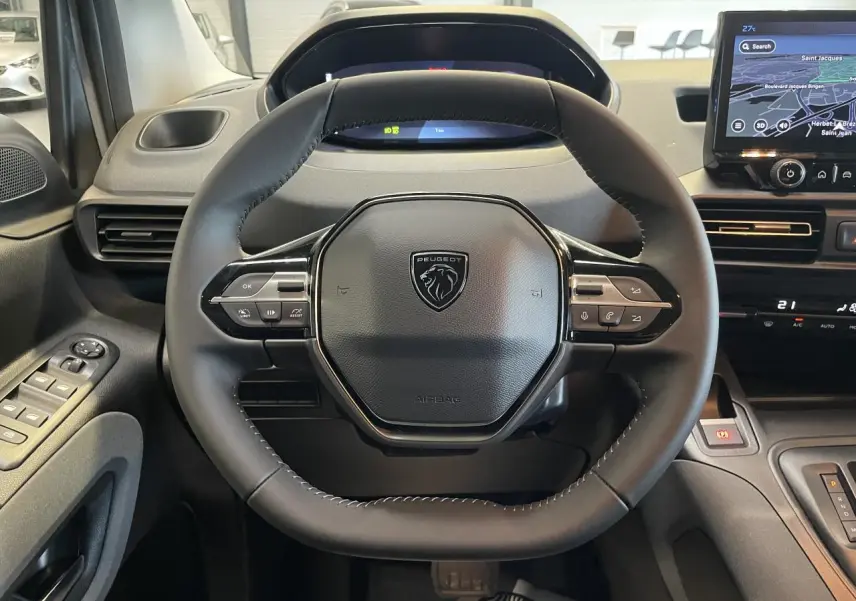 Vue rapprochée du volant cuir multifonction noir du Peugeot Rifter 2026 avec tableau de bord numérique et écran tactile GPS.