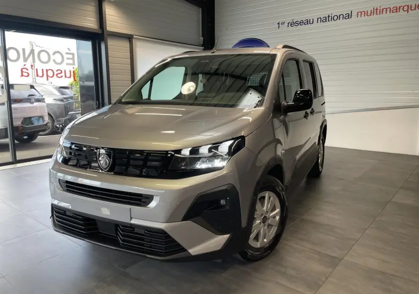 Peugeot Rifter gris Artense en 3/4 avant droit, avec calandre noire et jantes tôles 16 pouces en showroom.