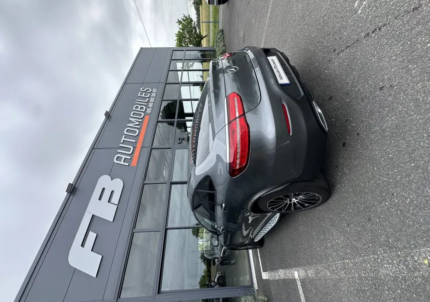 Vue 3/4 arrière droite d'un Mercedes GLC Coupé 250 D Fascination gris foncé stationné devant un concessionnaire.