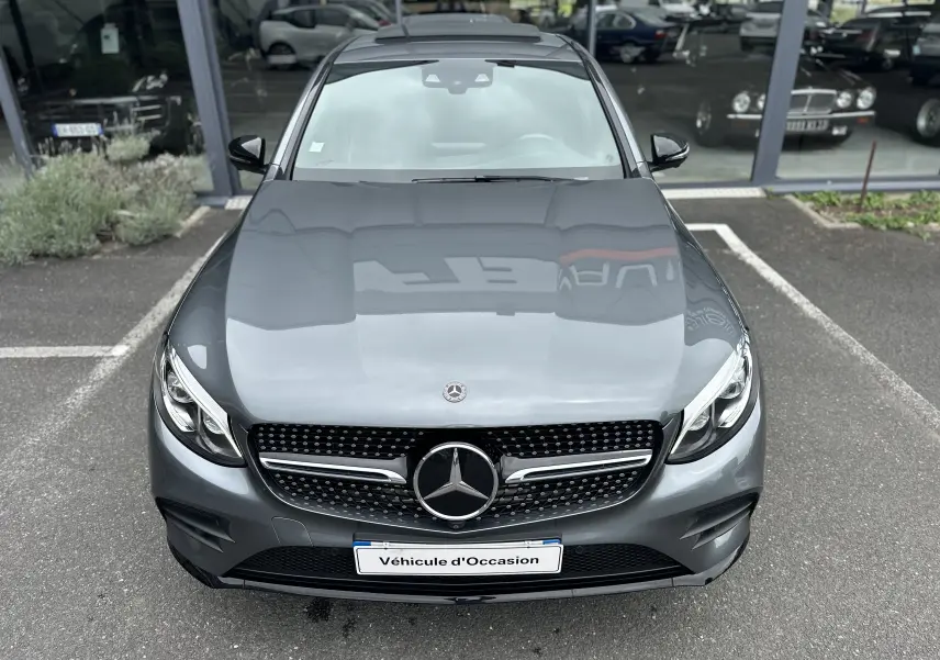 Vue avant d'un Mercedes GLC Coupé 250 D Fascination gris foncé, avec calandre étoilée et phares LED visibles.