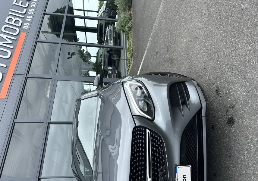 Vue 3/4 avant d'un Mercedes GLC Coupé 250 D Fascination gris foncé garé devant une vitrine de concession.