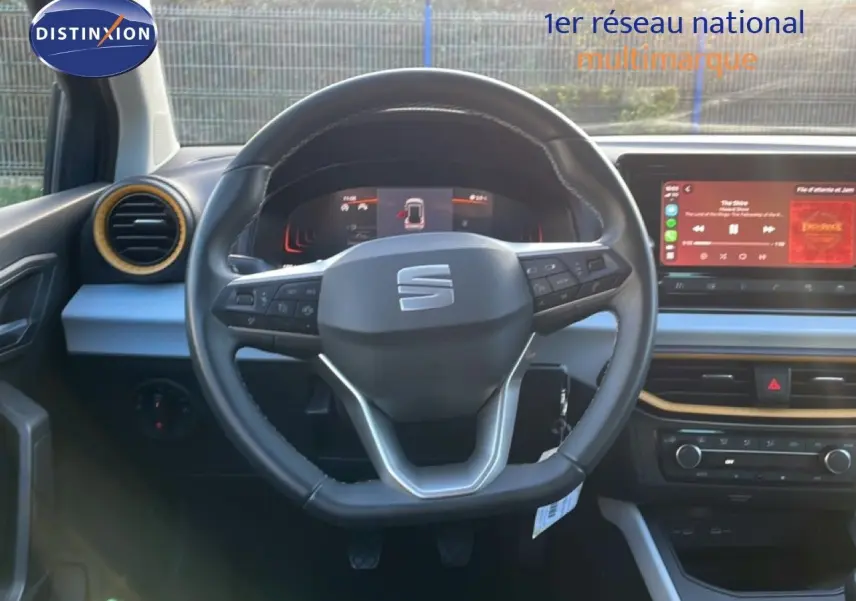 Vue intérieure centrée sur le volant cuir de la SEAT Arona 2025, avec tableau de bord numérique et écran tactile.