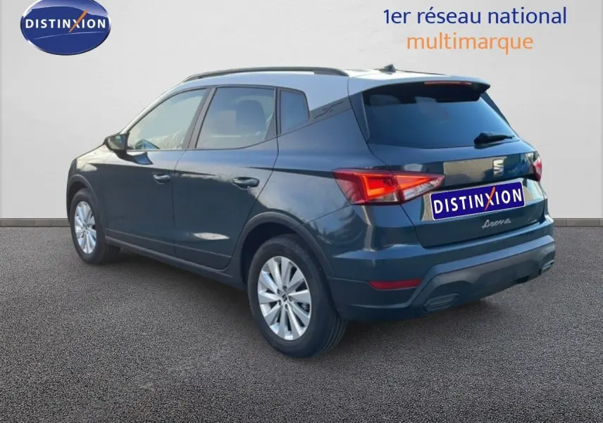 Vue 3/4 arrière droite d’un SEAT Arona gris magnétique métal avec toit noir, sur fond neutre en extérieur.